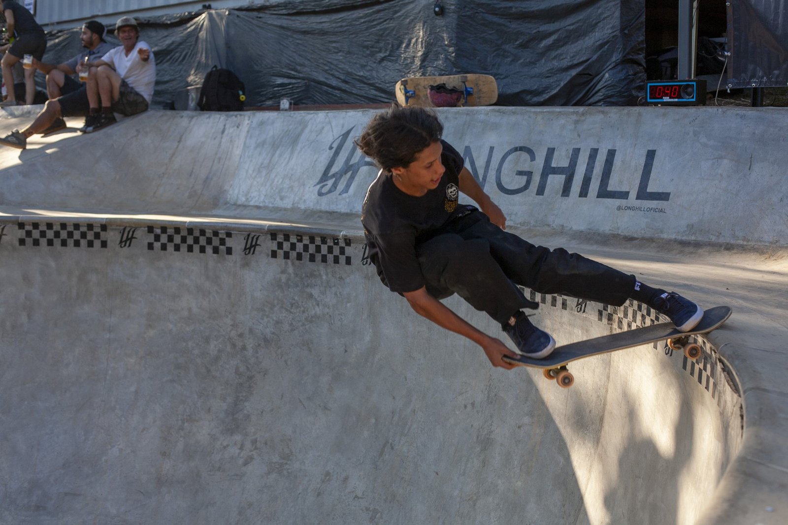 Grind no coping do bowl do QG, com LONGHILL pintado no muro