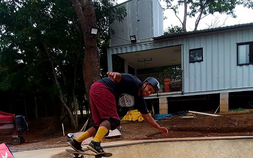 A casa de contêineres logo atrás da borda do bowl, com um skatista entrando na transição